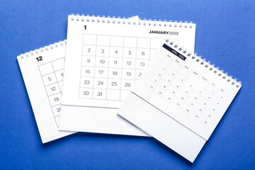 Flip paper calendars for December, January and April 2022 on blue background