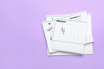 Stack of flip paper calendars for January, December, April 2022 and pins on color background