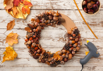 Beautiful wreath made of pine cones and acorns on white wooden background © Pixel-Shot