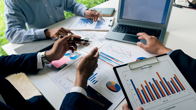 Close-up of young people having a business meeting in the office Businessmen chatting during a meeting with graphs and laptops with calculators to analyze financial computational data.