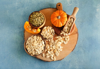 Bowls with natural pumpkin seeds on blue background