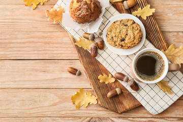 Autumn composition with cup of coffee, tasty cupcake and cookie on wooden background