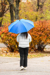 Woman walking with stylish bright umbrella in autumn park