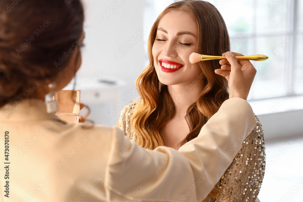 Sticker Makeup artist working with beautiful model in beauty salon