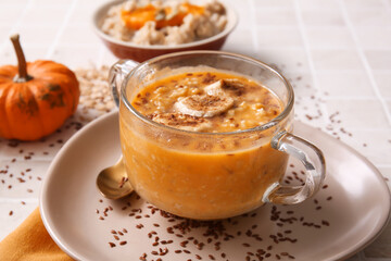 Pot of tasty oatmeal with pumpkin and banana on tile background