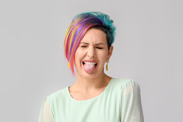 Grimacing woman with unusual hair on grey background