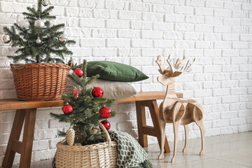 Beautiful decorated Christmas trees and reindeer near white brick wall
