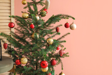 Christmas tree decorated with beautiful balls near color wall