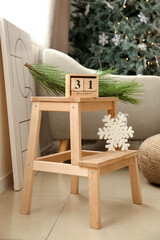 Wooden cube calendar with date DECEMBER 31 and snowflake on wooden stepladder stool in living room