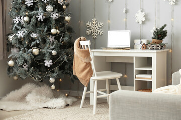 Workplace with modern laptop in room decorated for Christmas