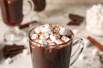 Glass cup of tasty hot chocolate with marshmallows on light background, closeup