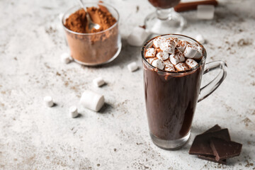 Glass cup of tasty hot chocolate with marshmallows on light background