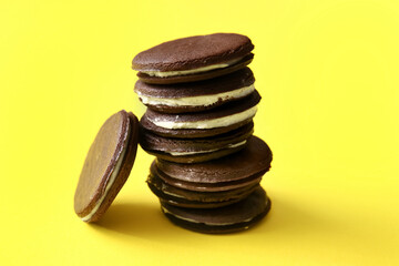 Fototapeta na wymiar Tasty chocolate cookies with cream on yellow background