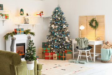 Interior of festive living room with modern workplace, Christmas trees and fireplace