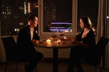 Valentine's day dinner by candlelight, couple in love on a date, night meeting man and woman with wine, romantic date at home