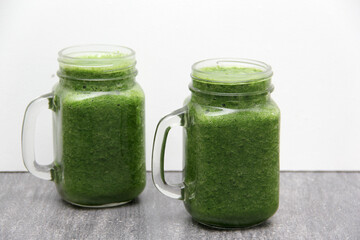 Green juice made from vegetables such as cucumber, lemon, spinach, chard, celery served in a glass mason jar for a healthy, vegan and nutritious breakfast
