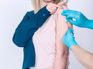 Doctor in blue gloves puts a woman a vaccine. Coronavirus concept