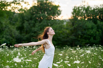 cheerful woman in a field with flowers in a white dress in nature