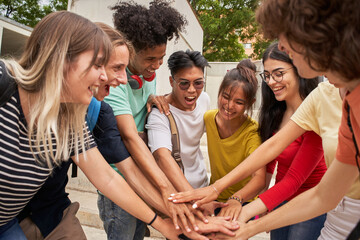 Group of teenage friends high-fiving each other, happy and motivated, having a good time together....