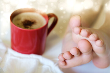 A cup of coffee or hot chocolate and white chrysanthemum and female bare feet. Comfort aesthetics...