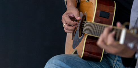 Close up shot of guitarist playing acoustic blues guitar on black background with copy space
