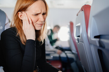 a woman on an airplane has a headache and an earache while flying on an airplane