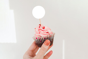 Mockup of cupcake topper holding in hand. Round label cupcake mockup for your design.