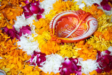 close up shot of flower petal rangoli with handmade painted petal shaped earthenware diya lamp used in decoration for indian festival of diwali, wedding, new year