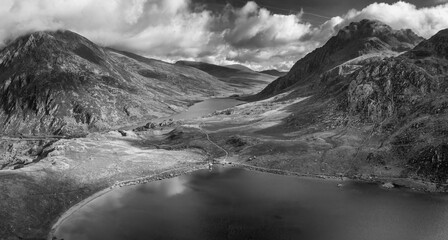 Black and white Aerial view of flying drone Epic Autumn Fall landscape image of view along Ogwen vslley in Snowdonia National Park with moody sky and mountains