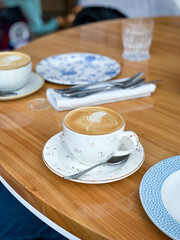 a cup of cappuccino in a white cup on a wooden table in a restaurant