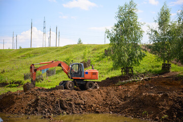 Fototapeta premium Excavator on earth construction works in a ravine on a sunny summer day