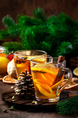 Winter hot healing tea with ginger, honey, lemon and spices in glass cup with steam, rustic wooden background. Christmas table settings