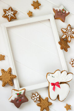 Gingerbread reindeer Christmas Cookie , stars, snowflakes on white wooden board, wooden phote frame with empty space.Christmas border, Christmas template for sale, greeting cards, advertising