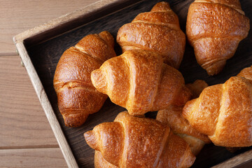 Homemade croissants on wooden tray.