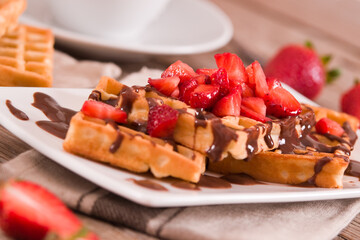Waffles with strawberries and chocolate cream.