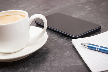 Mobile phone, coffee with milk and notepad for writing notes. Work or relaxation