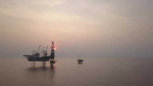 Aerial view of the jack up rig shot during sunset time (silhouette scene). Fly around the jack up rig with a drone.
