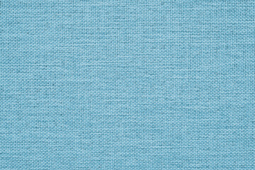 Close-up of light blue woven surface. The texture is similar to len. Abstract background from fabric. Textured tinted backdrop in a graceful shade. Macro