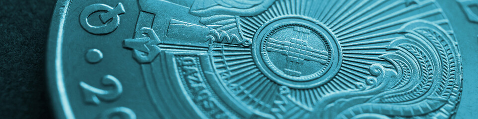 Fragment of Kazakh 50 tenge coin with the country emblem and focus on shanyrak. Close-up. Turquoise...