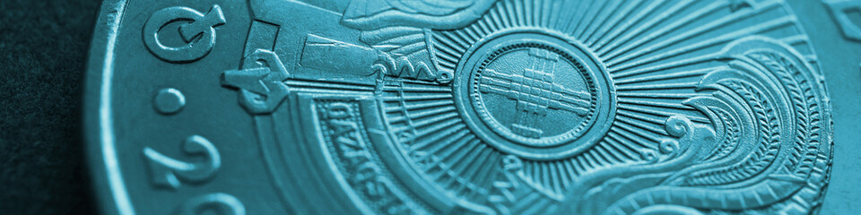 Fragment of Kazakh 50 tenge coin with the country emblem and focus on shanyrak. Close-up. Turquoise tinted banner or headline for Kazakh economy or state. Macro