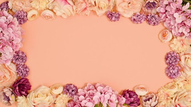 Floral frame made of pastel spring flowers on pastel orange theme. Stop motion