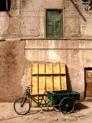 Fototapeta na wymiar Bicycle pulling cart against an old building