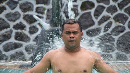 Man taking a shower with outdoor shower. ritual by bathing in holy water. Man relaxing in massage pool. frolicking in the shower.