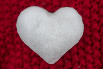 Knitted red background with heart of snow. Love winter. Valentine day background.