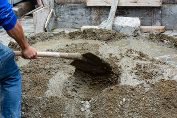 worker mixes cement with shovel