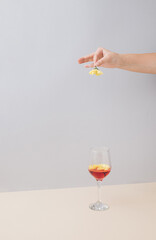 Women hand dropping daisy flower in wine glass.Grey and beige background with copy.Minimal celebrate and spring concept.