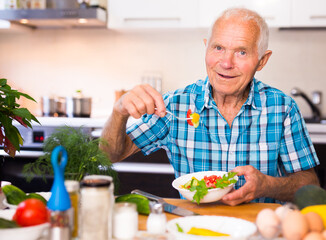 elderly man eating fresh vegetable salad at home