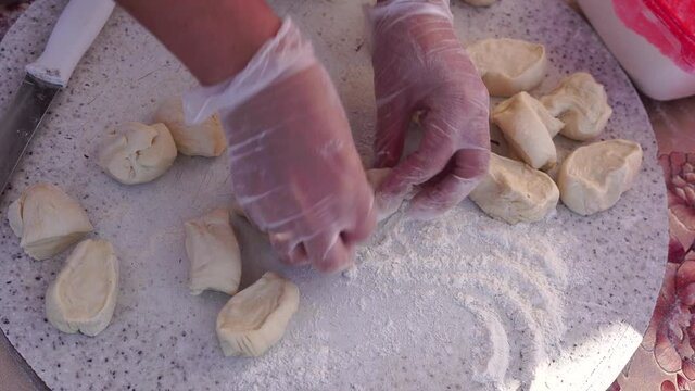 Adult woman making chebureks - roasts chebureks in pan, prepares meat pies, working with the dough and filling, close-up. Fried flatbread piadina naan pita tortilla shelpek cheburek. Street food.