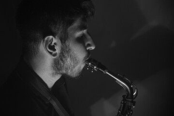 jeune musicien qui joue du saxophone. Ambiance jazz avec de la fumée et l'image en noir et blanc