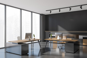 Corner view on dark office interior with two desks, desktops